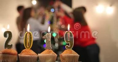 新年庆典。 在一家欢乐的公司庆祝“新”的到来之前，桌上摆满了2019年数量的蜡烛的纸杯蛋糕
